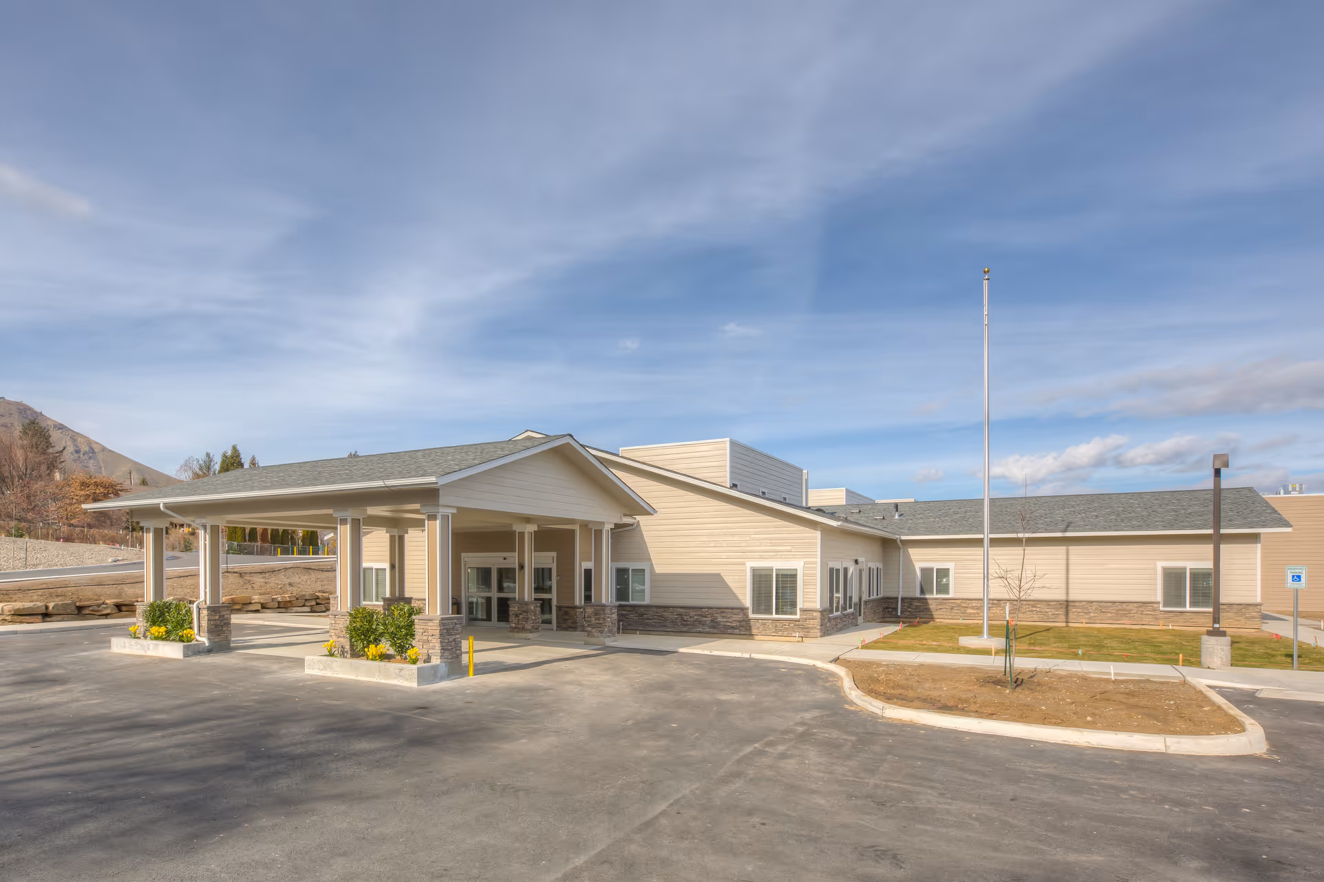 Exterior view of a single-story nursing facility with covered entrance and surrounding parking.