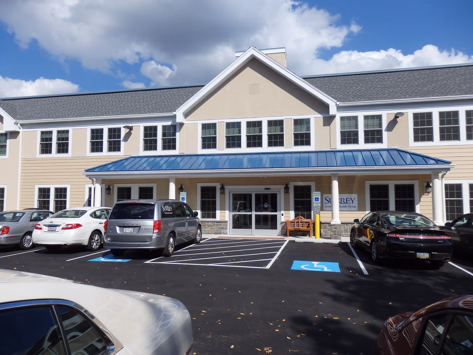 Front view of Surrey Home Care Services building with a blue-roof entrance and parked cars.