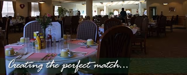 Spacious dining room in a senior living facility with many tables set for meals.