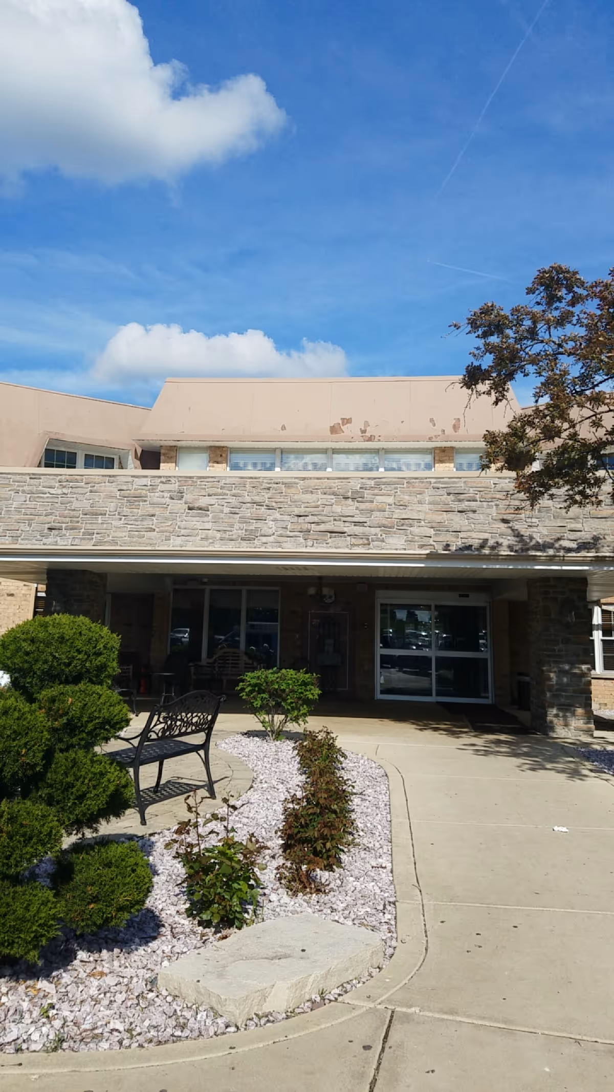 Front exterior of Burgess Square Healthcare & Rehab Centre with entrance and stone facade.