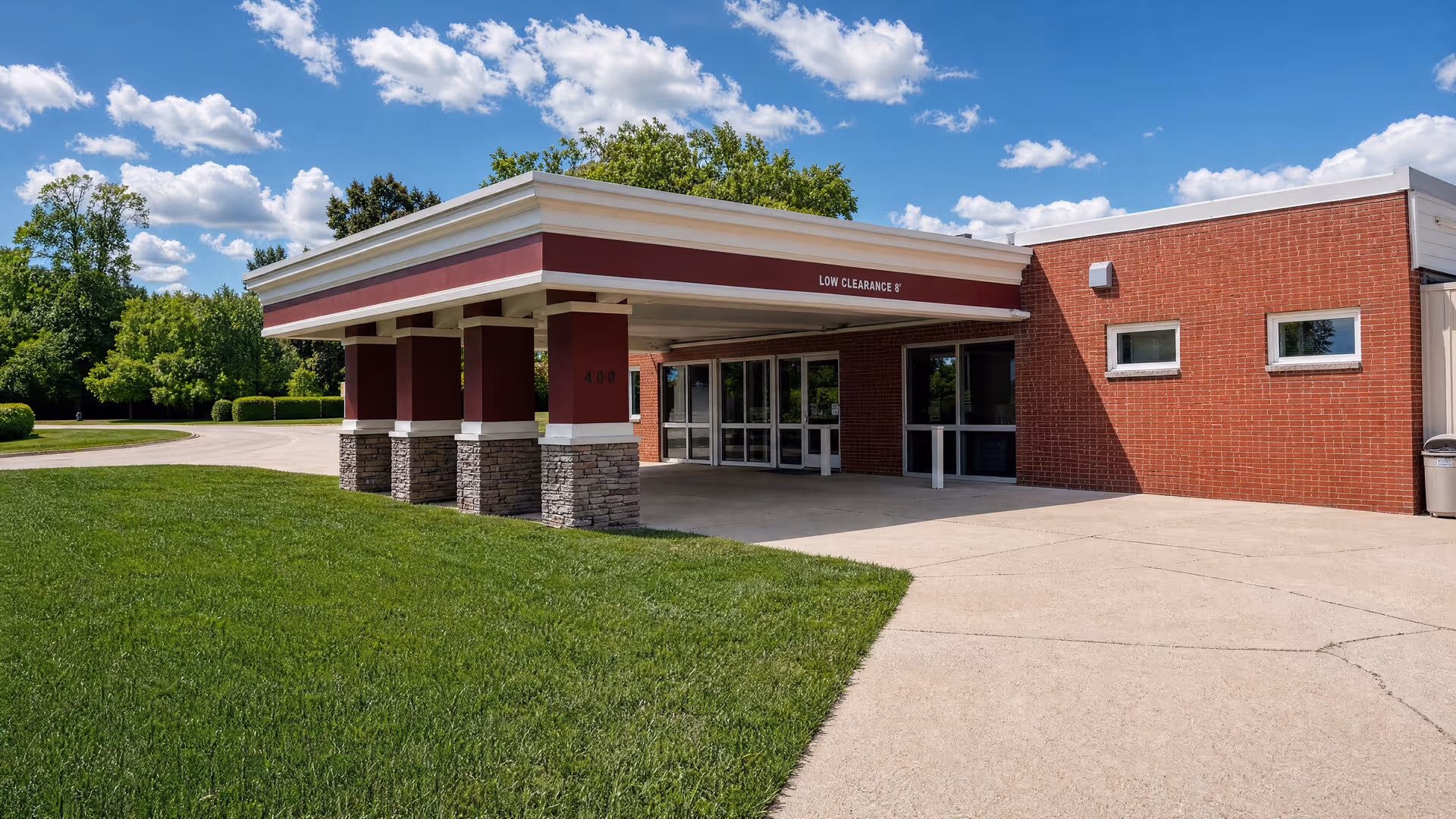 Facade of Lake Mills Care Center with brick exterior, porte-cochère, and glass entry doors