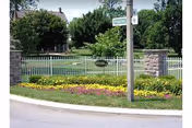 Exterior view of Highland Glen featuring a stone wall, white fence, and landscaped flower bed.