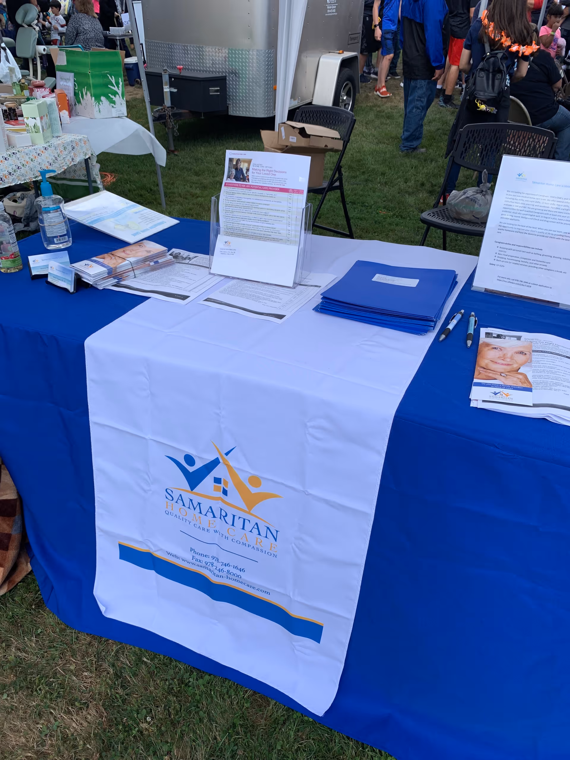 Outdoor information booth for Samaritan Home Care with brochures and blue tablecloth.