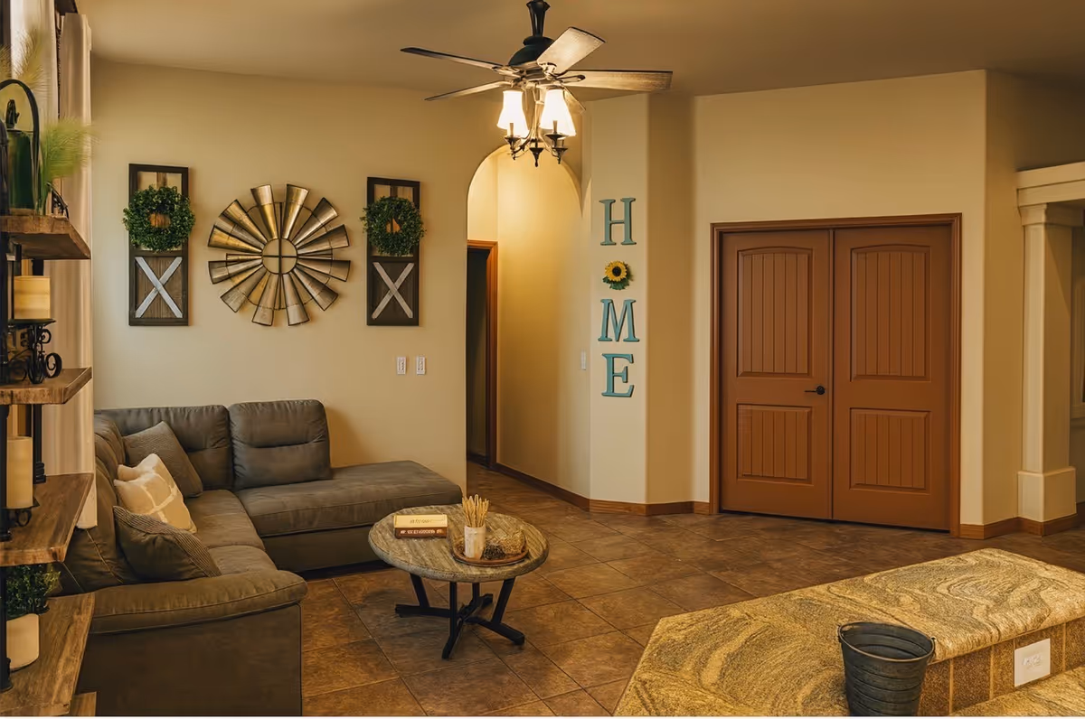 Cozy senior living room with gray sectional, coffee table, ceiling fan, and wall decor.