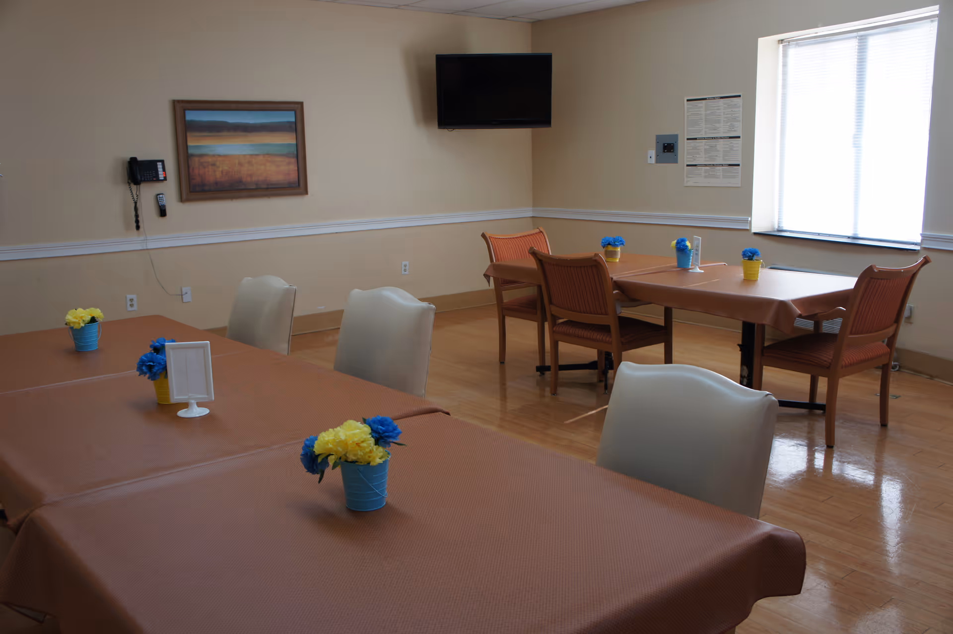 Dining room in a senior facility with pastel tablecloths and flower centerpieces.