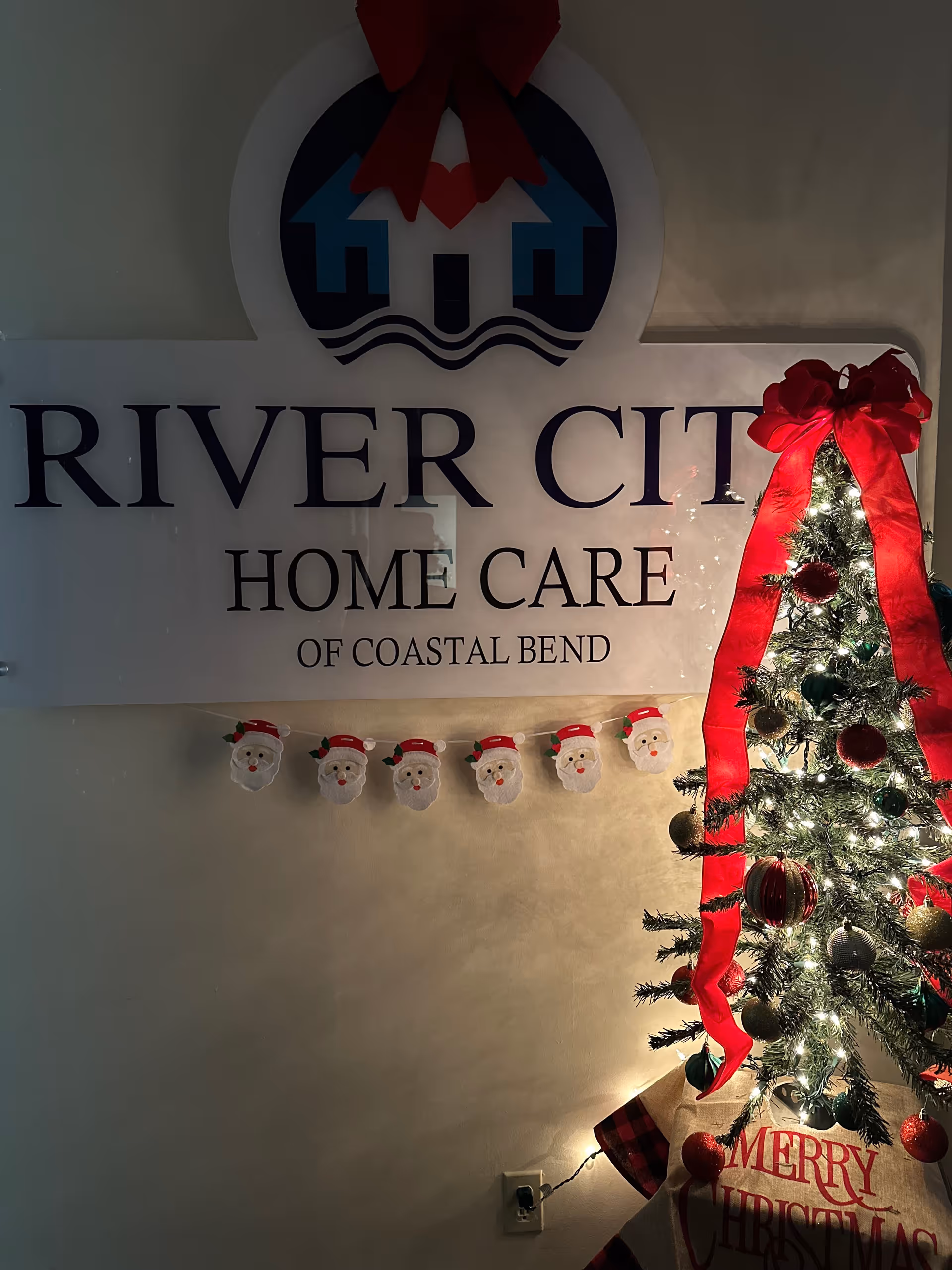 Indoors, a River City Home Care sign with a Christmas tree.