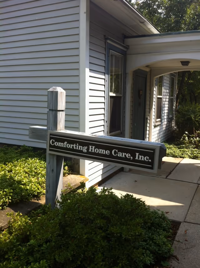 Exterior view of a house-like facility with a sign reading Comforting Home Care, Inc.