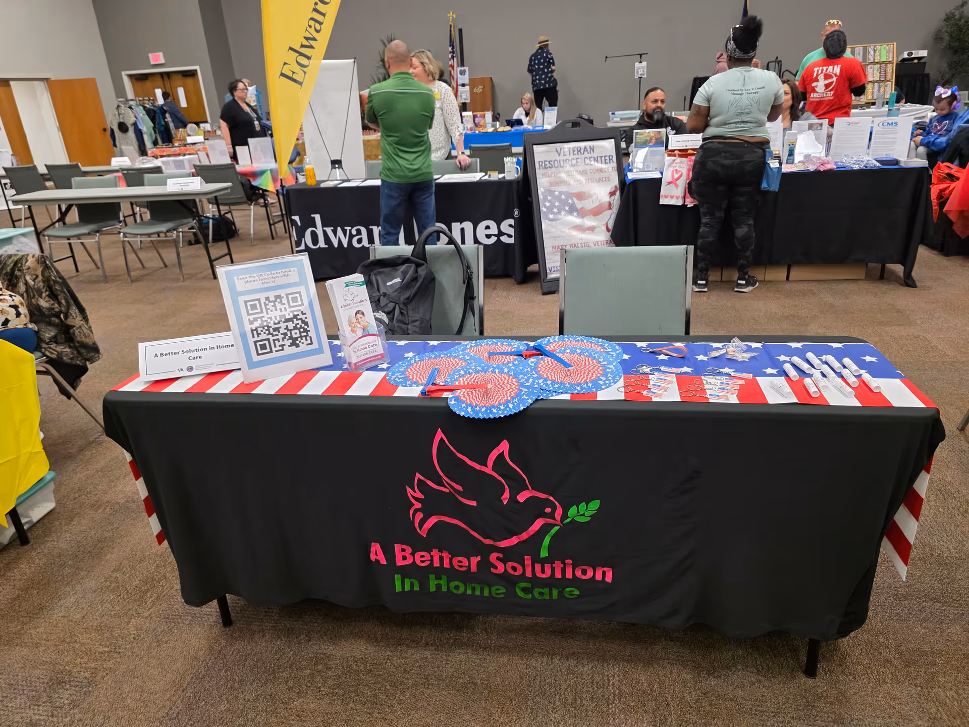 An indoor expo table for A Better Solution In Home Care Tulsa with staff and attendees.