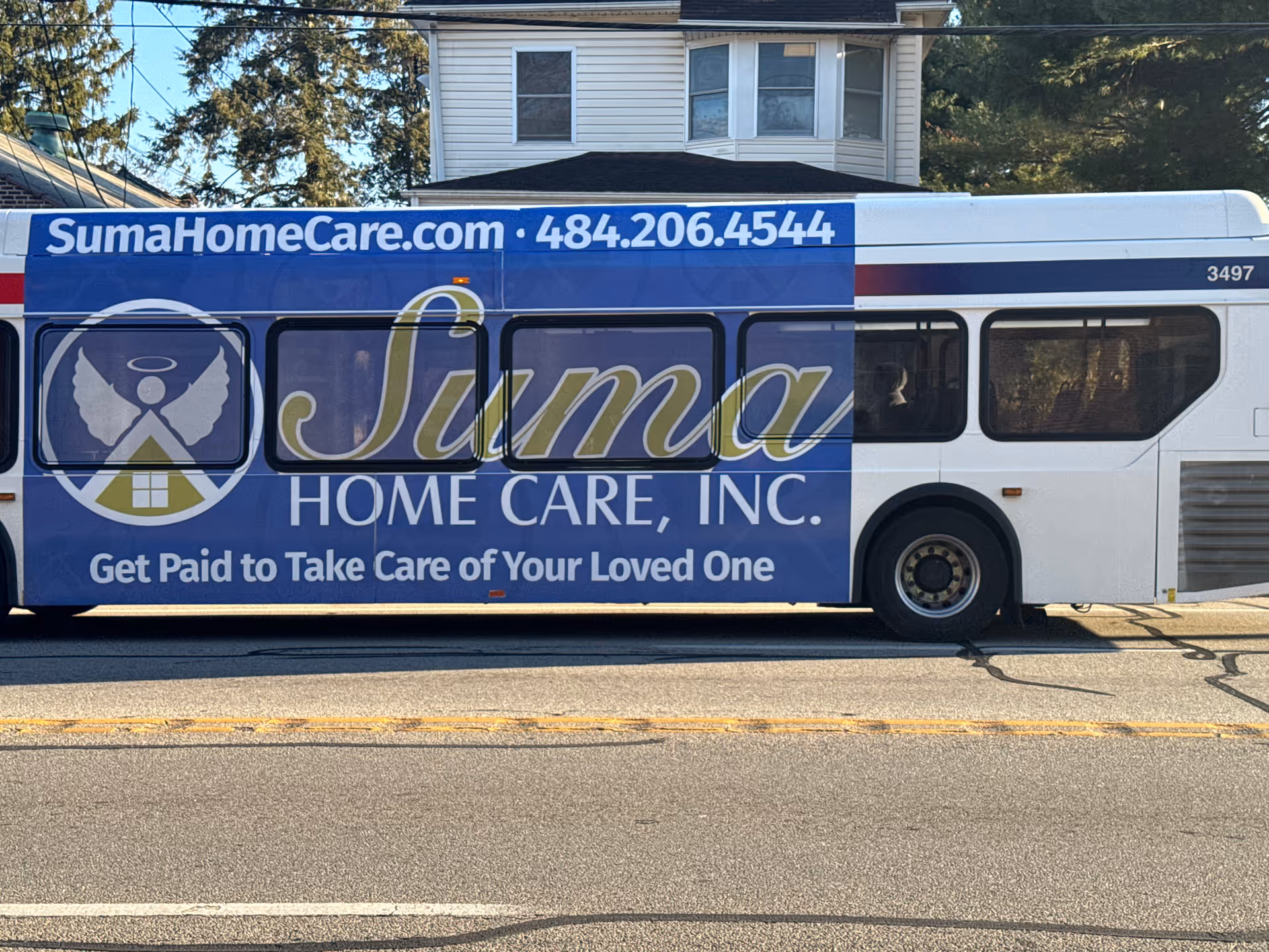 Blue bus advertising Suma Home Care, Inc. with website and slogan across its side.