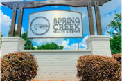 Entrance sign reading Spring Creek Health & Rehab mounted between white brick columns with shrubs.