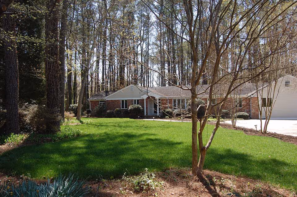 Front view of a single-story brick senior living facility with a green lawn and trees.