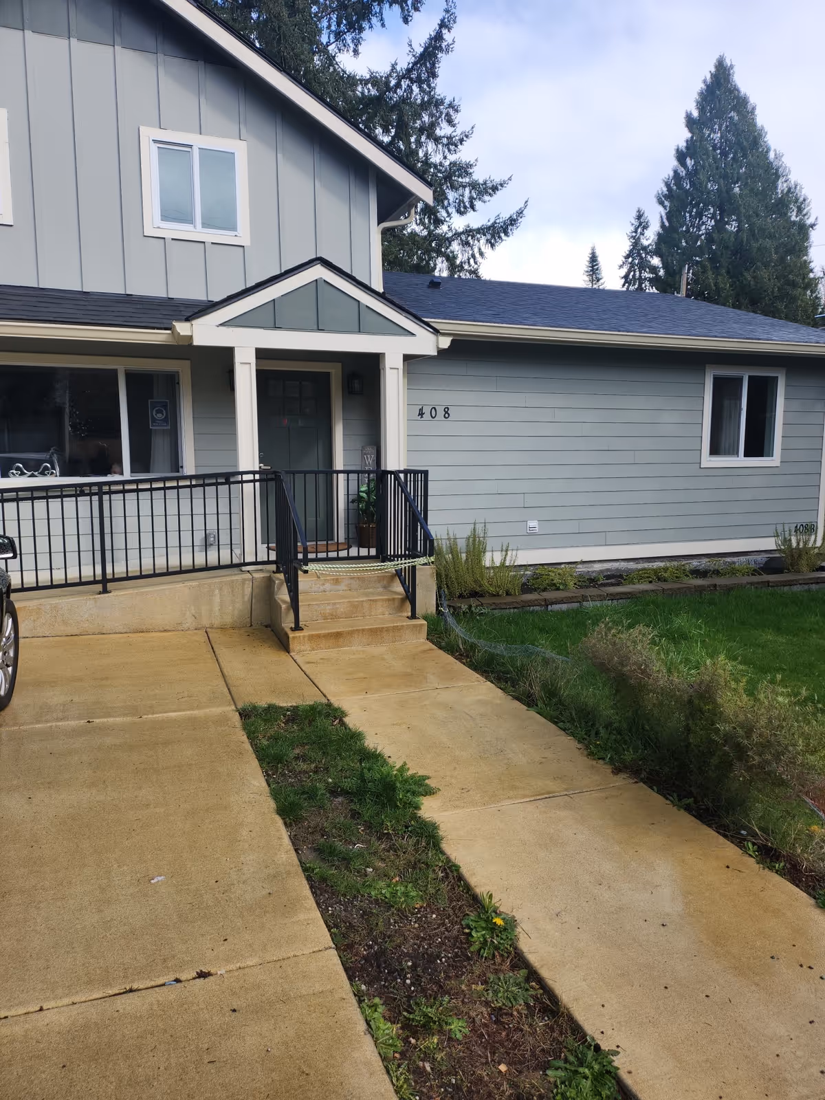 Blue-gray senior living facility exterior with front entrance, stairs, and railings.