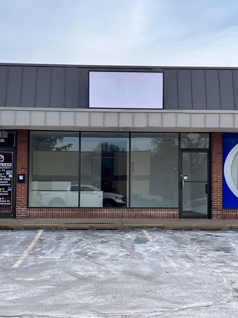 Storefront of Priority Care Unlimited building with large glass windows and a blue logo.