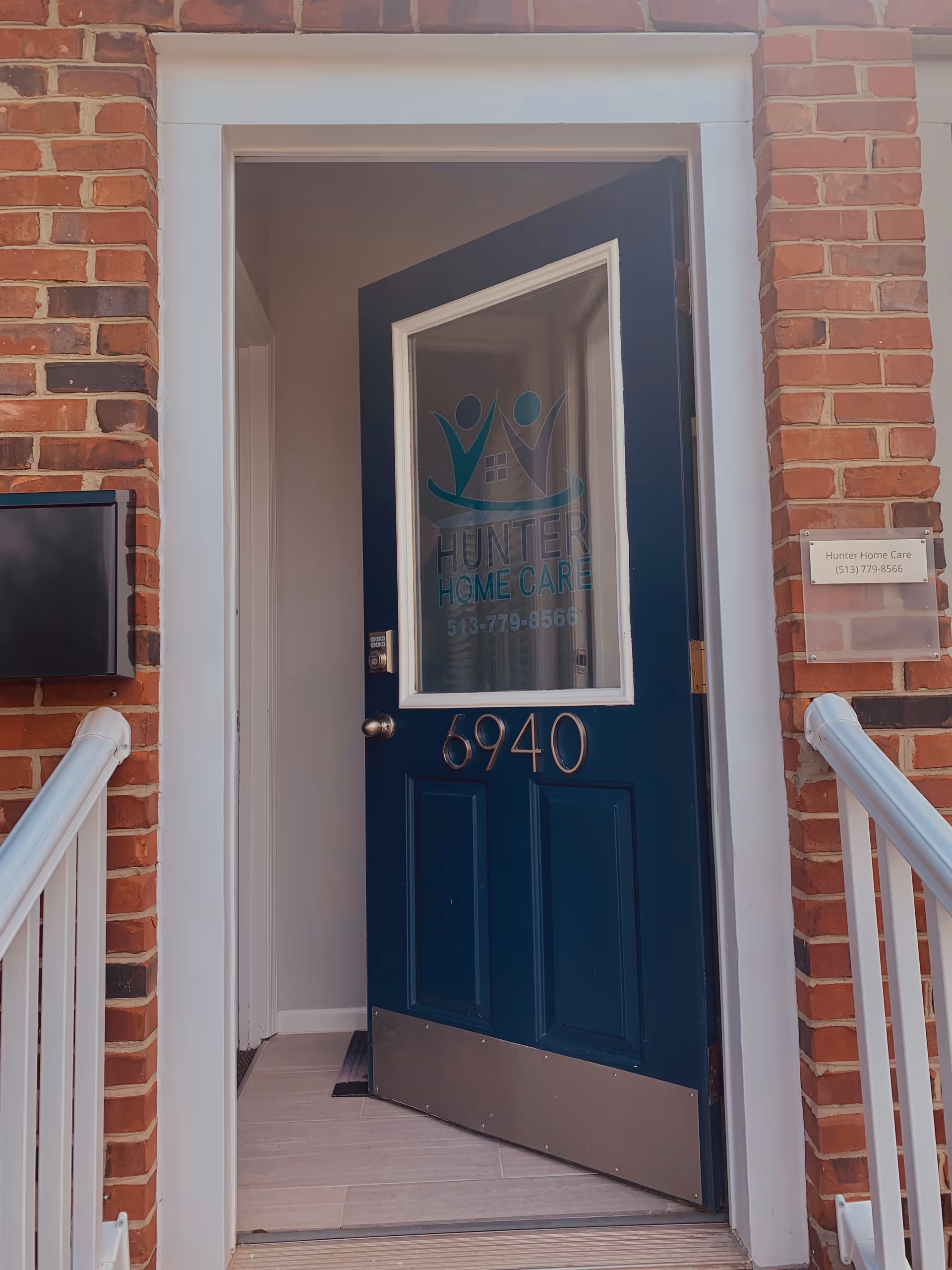 Blue front door with Hunter Home Care logo in a brick entryway.