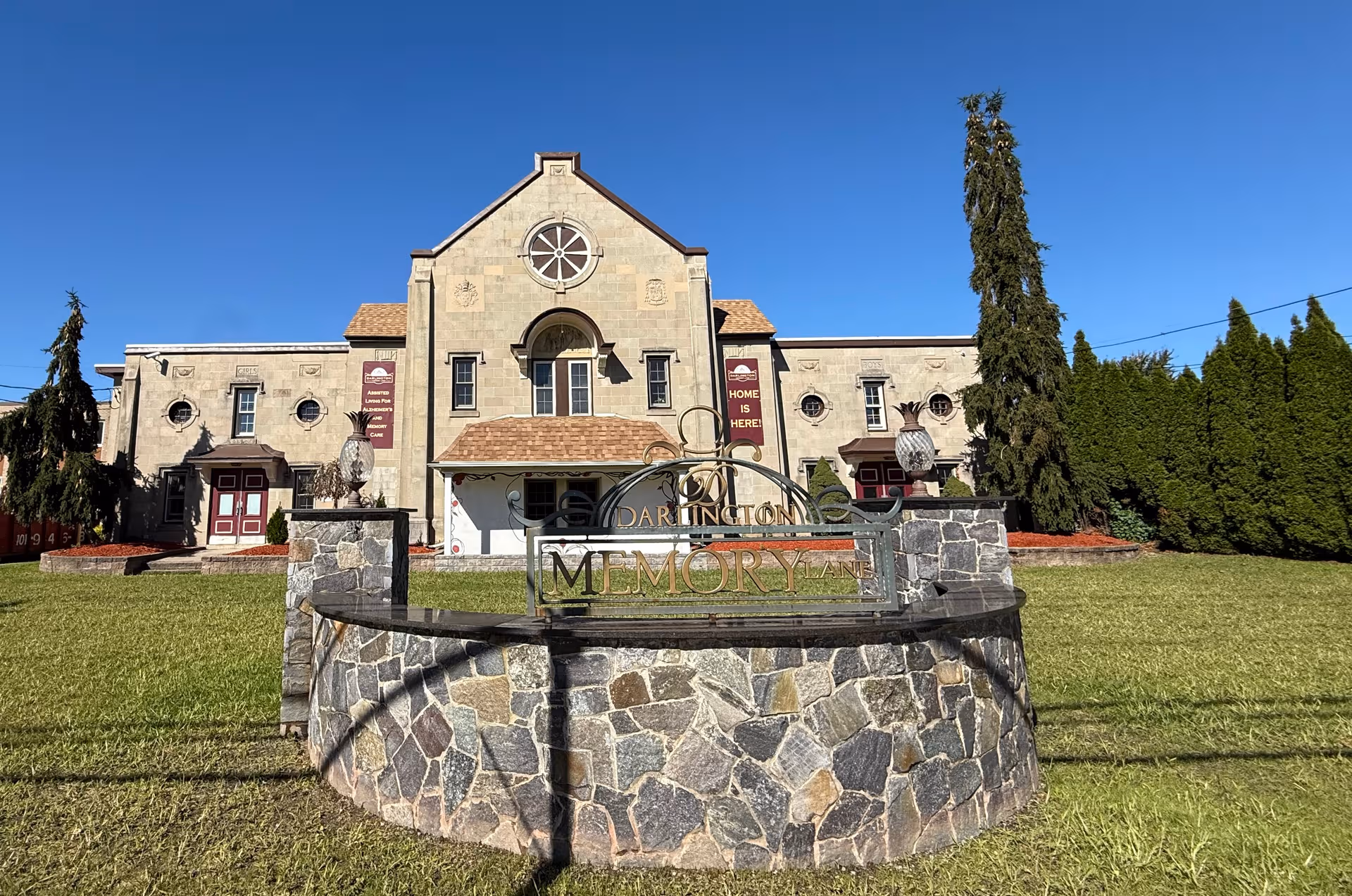Exterior view of a stone senior living facility with a front sign reading Darlington Memory Lane.