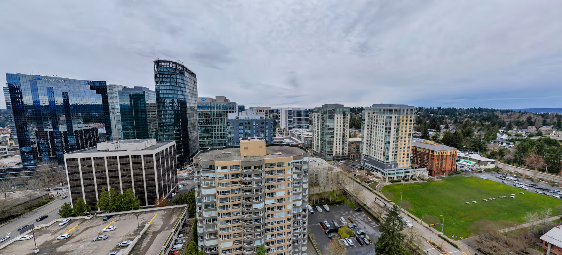 Aerial view of modern glass towers and mid-rise buildings with a green field.