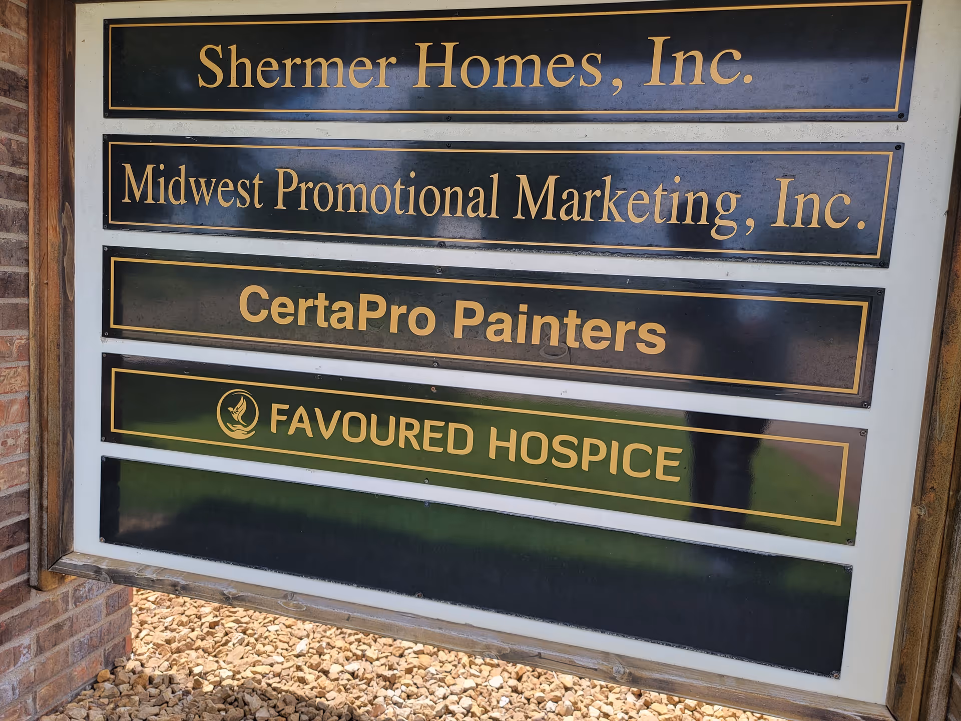 Exterior signboard listing multiple company names, including Favoured Hospice.