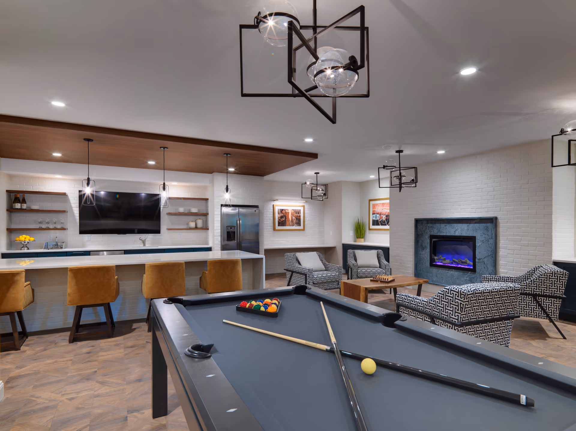 Modern senior living lounge with pool table, fireplace, and bar area.