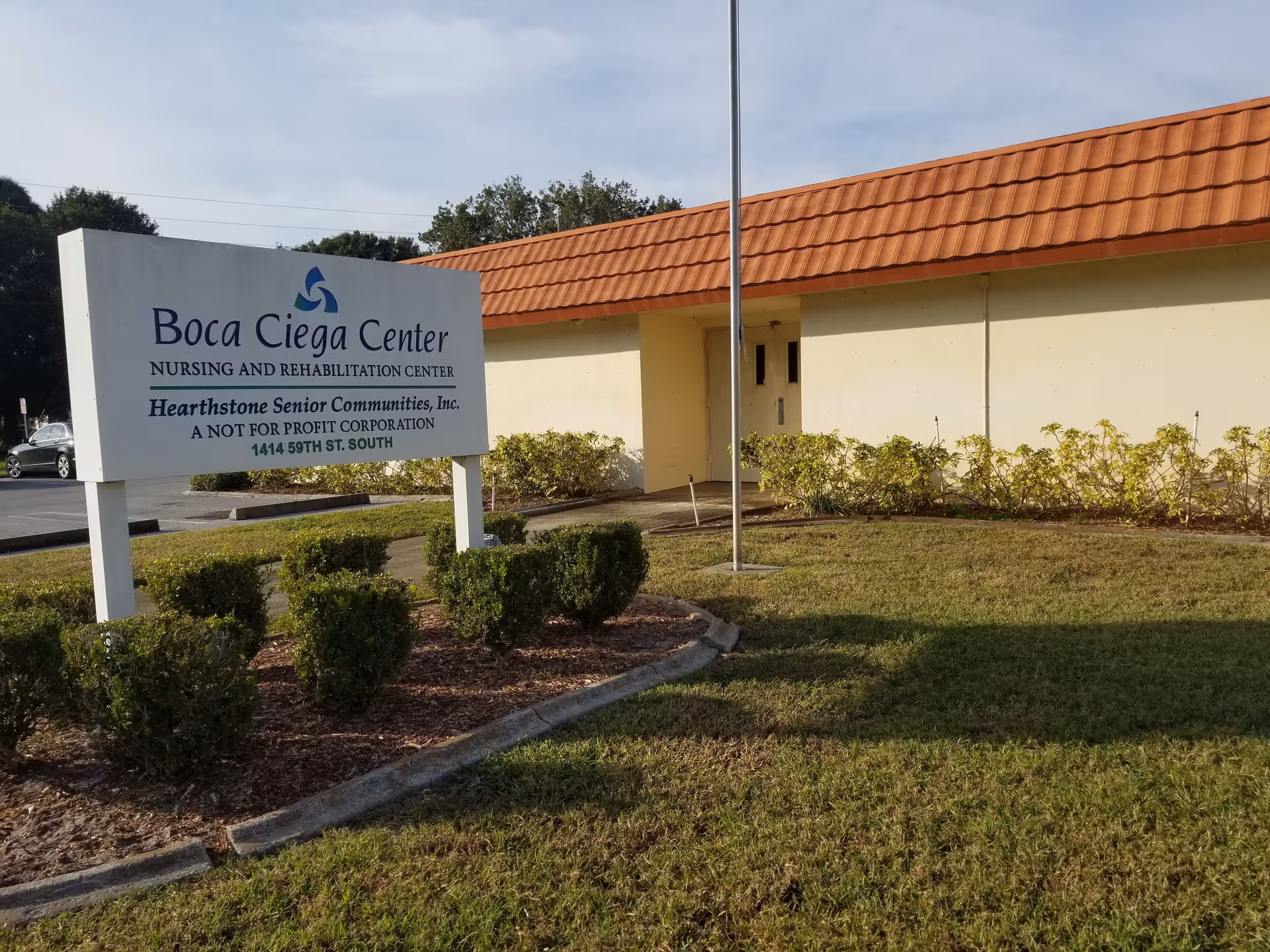 Front view of Boca Ciega Center sign with beige building and orange roof.