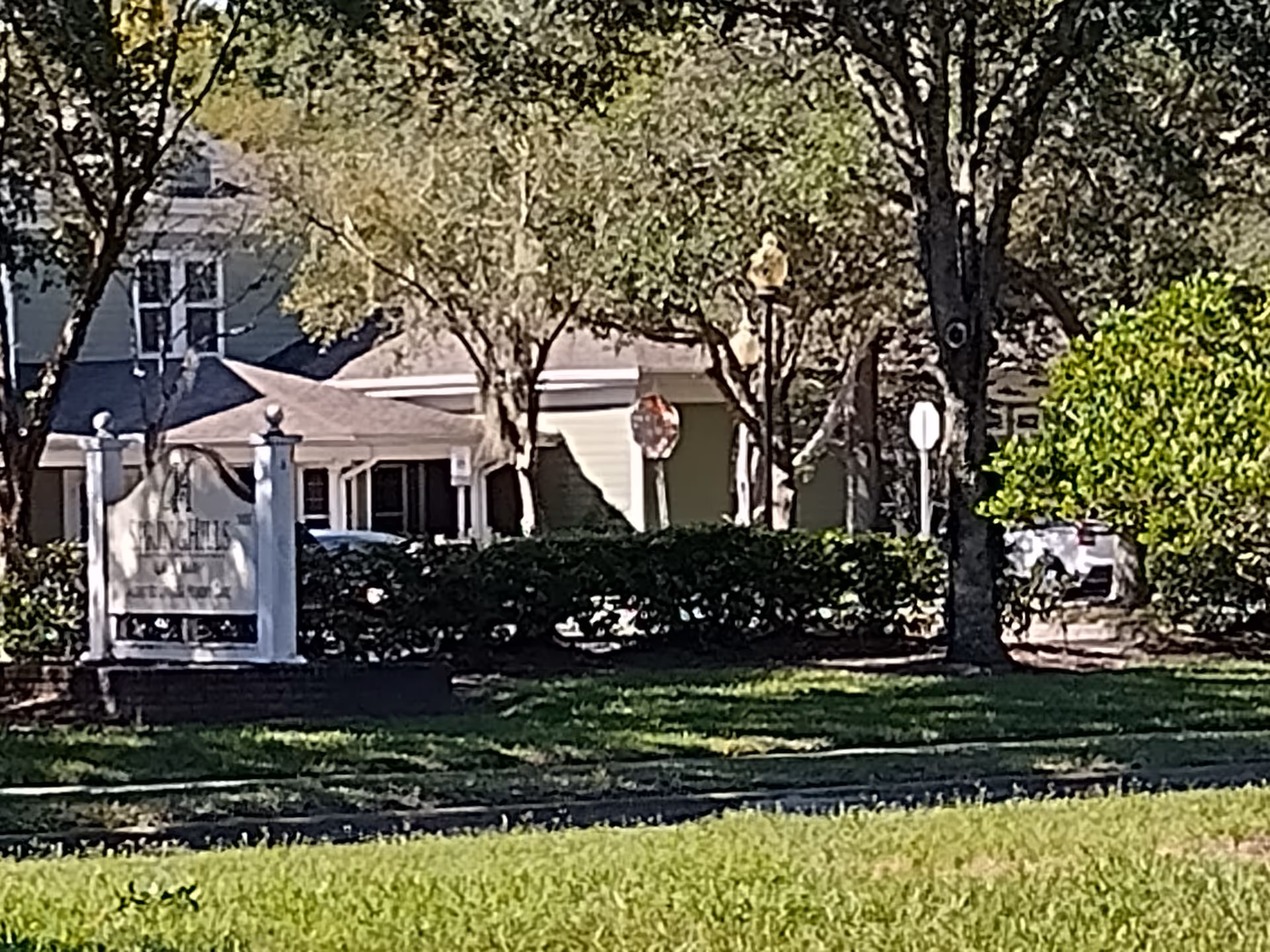 Exterior view of Spring Hills Lake Mary with sign and trees by the entrance.