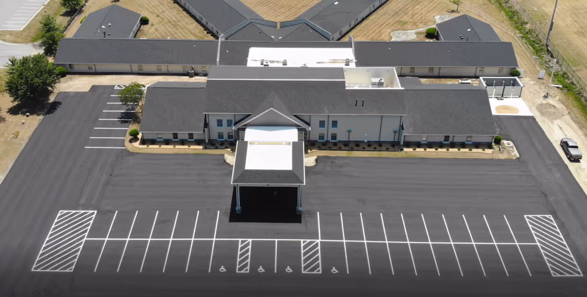 Aerial view of a modern senior living facility with a large parking lot and main entrance