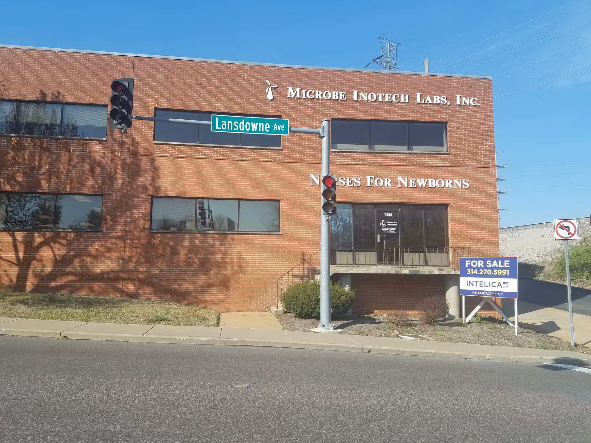 Brick building facade with Nurses For Newborns sign and street traffic light.
