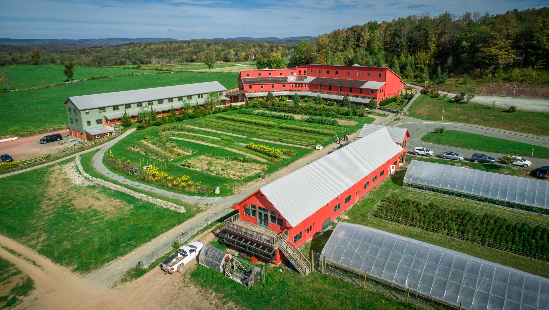 Aerial view of The Center for Discovery campus with red buildings, gardens, and greenhouses.