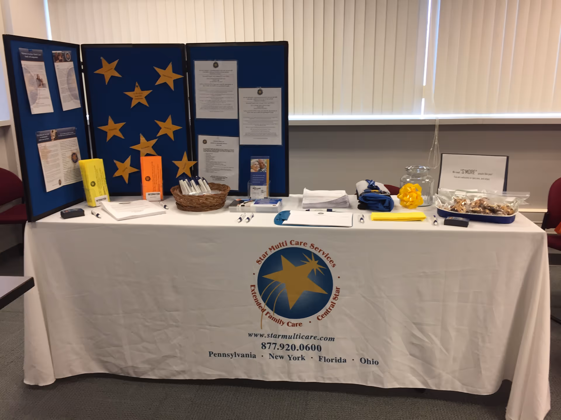 Information booth table with blue star display boards and brochures in an indoor facility lobby.