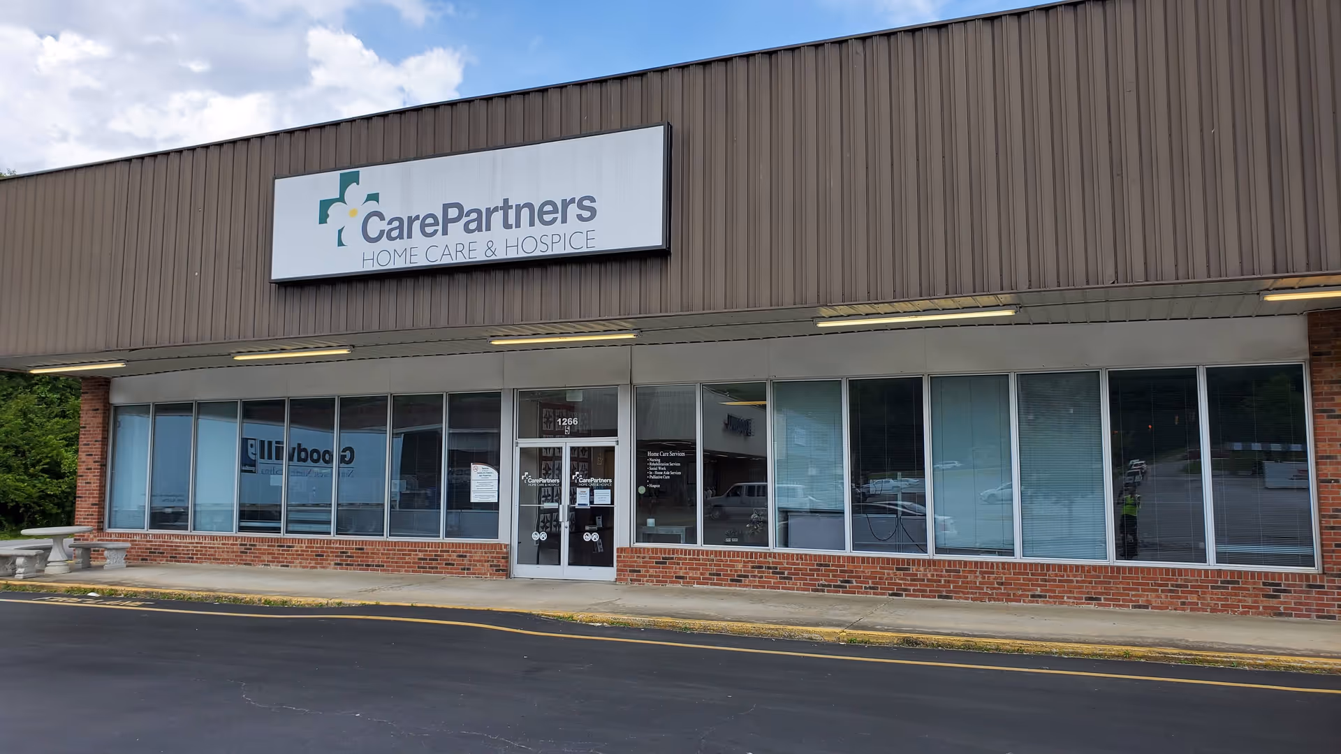 Front view of CarePartners storefront with large windows, brick base, and sign.