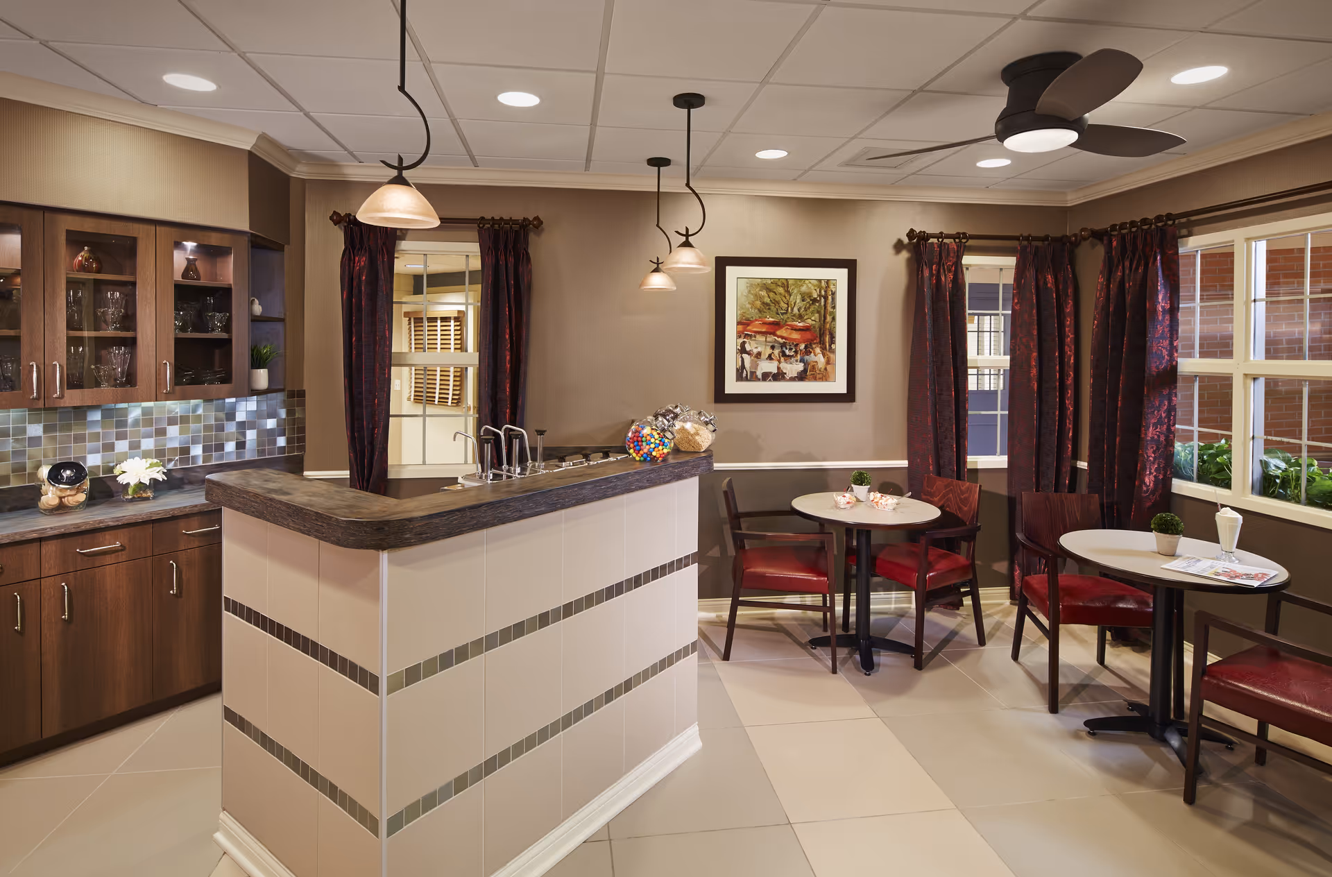 Modern communal kitchenette with island, cabinets, and small dining tables.