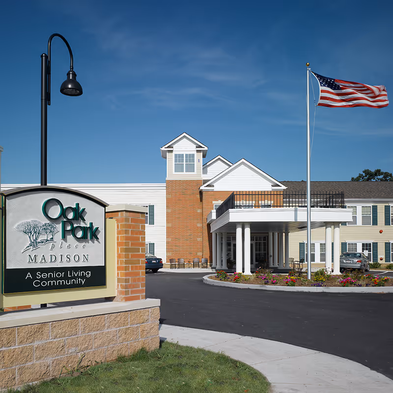 Exterior view of Oak Park Place Madison senior living community entrance and flag