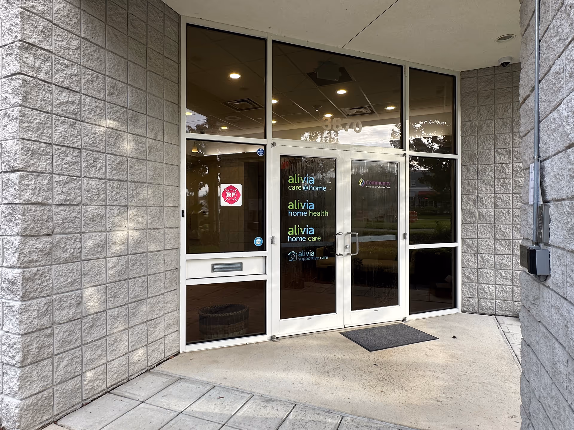 Exterior glass-door entrance of a care facility with stone walls and logos.
