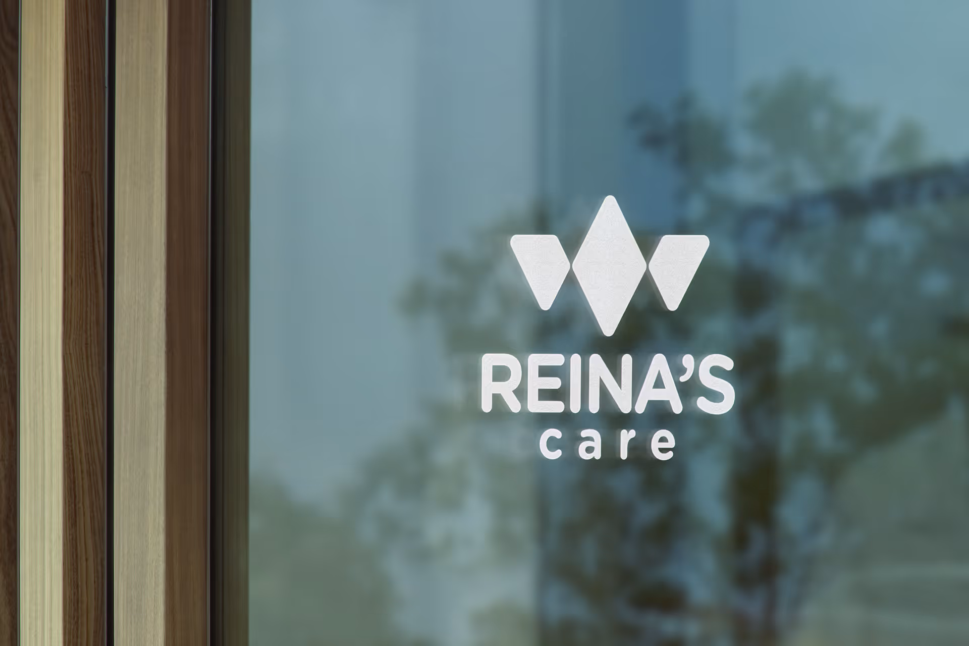 Glass entrance with Reina's care logo and wooden frame, reflecting trees outside.