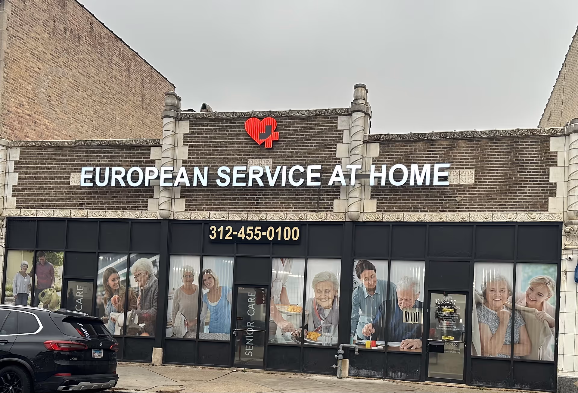 Brick storefront with European Service at Home sign and large window graphics of seniors.