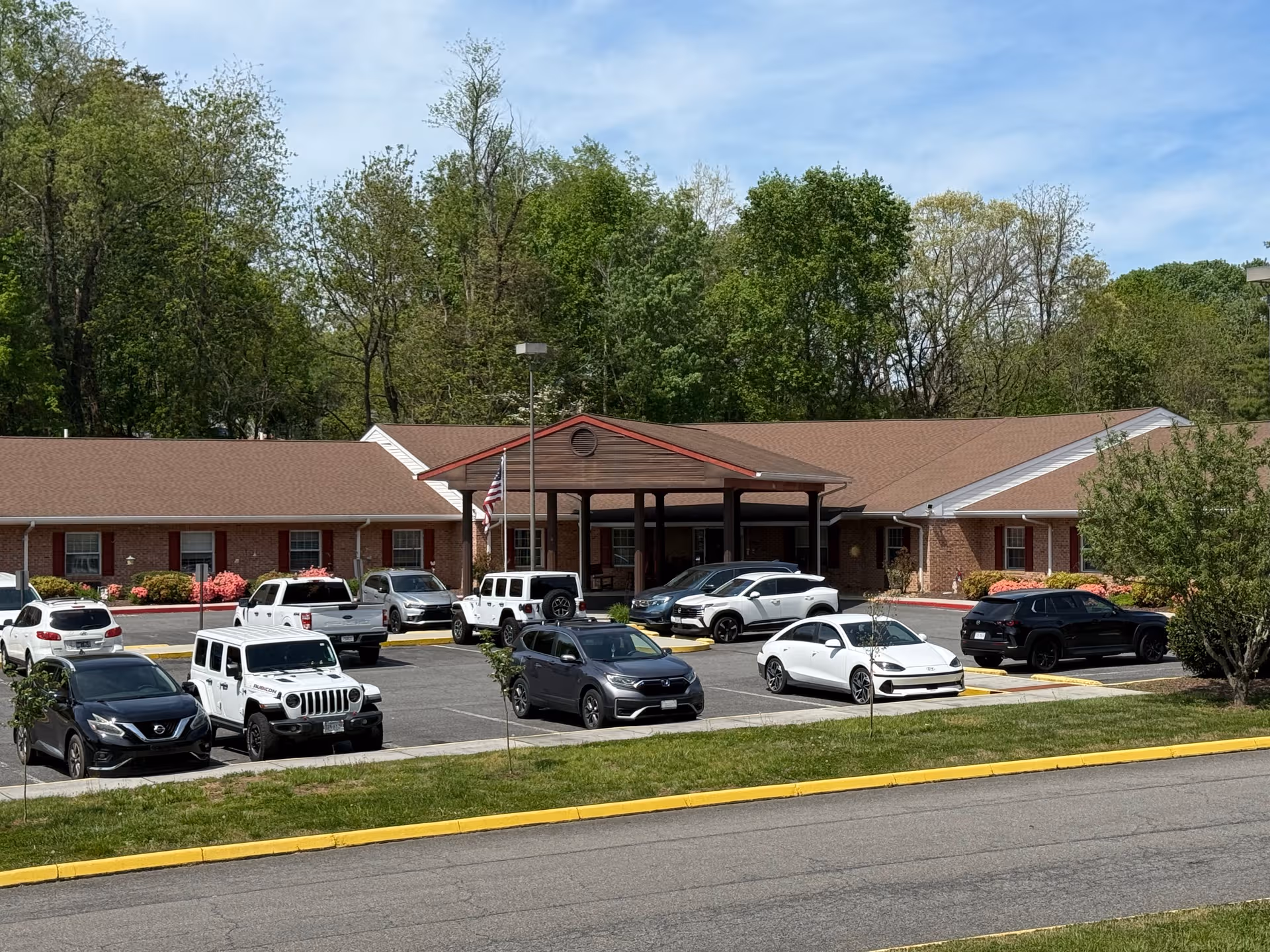 Single-story brick assisted living facility exterior with a covered entrance and a parking lot.