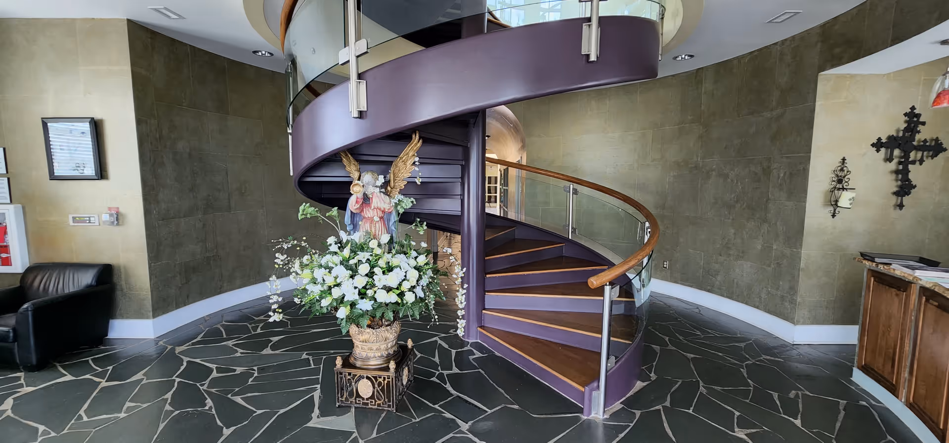 Modern lobby features a purple spiral staircase and a large floral arrangement centerpiece.