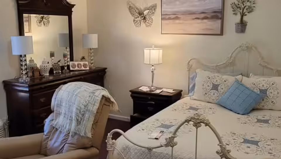 Cozy bedroom with a wrought-iron bed, nightstands, lamps, dresser, and decorative wall art.