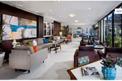 Spacious senior living lounge with modern seating, artwork, and large windows overlooking outdoors.