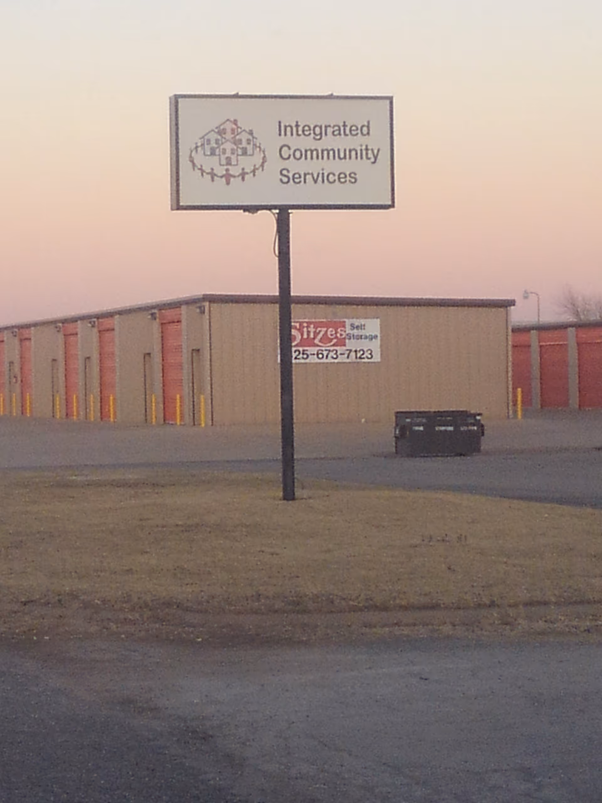 Tall sign for Integrated Community Services in front of a beige storage building.