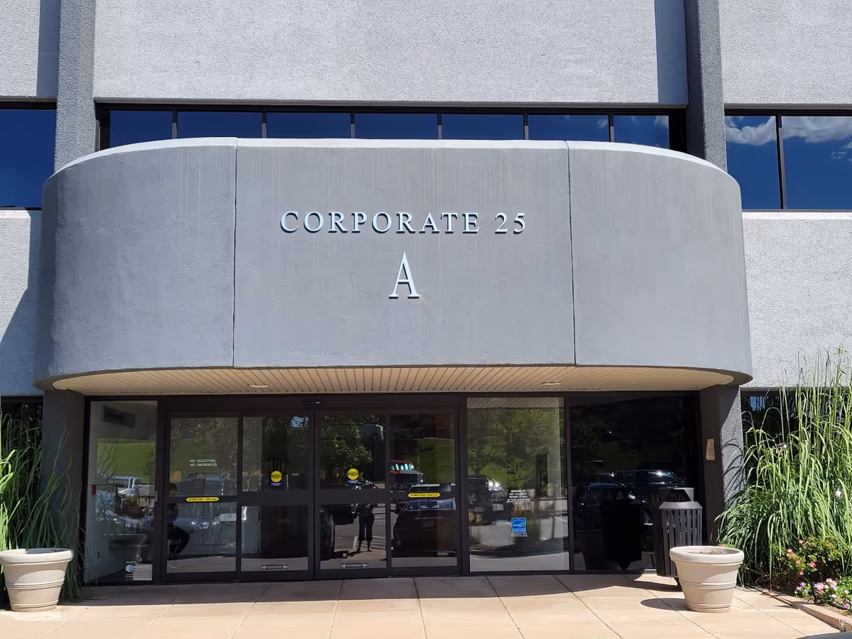 Front of a modern building with curved concrete entry and glass doors.