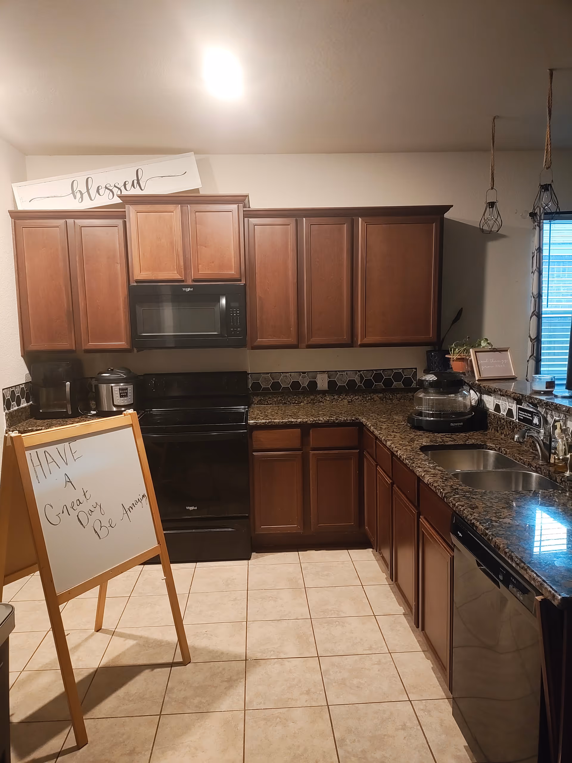 U-shaped kitchen with dark wood cabinets, granite counters, and a whiteboard sign.