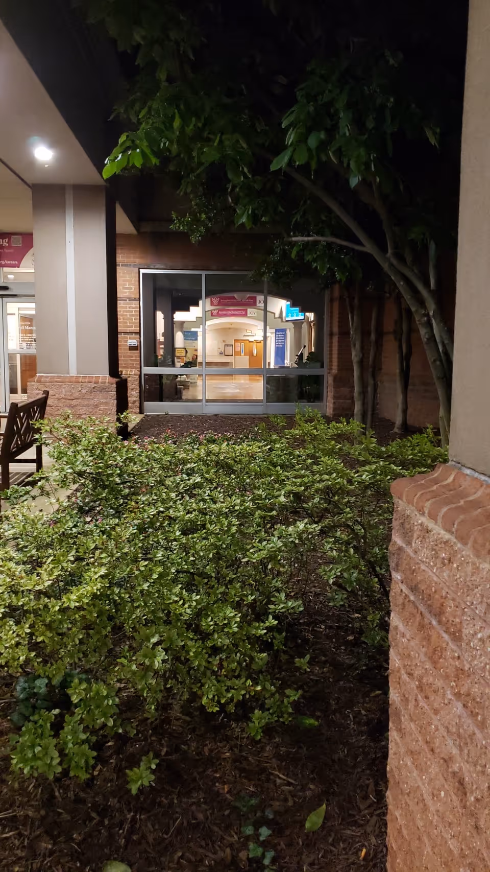 Exterior view of Carroll Manor entrance with glass doors and greenery.