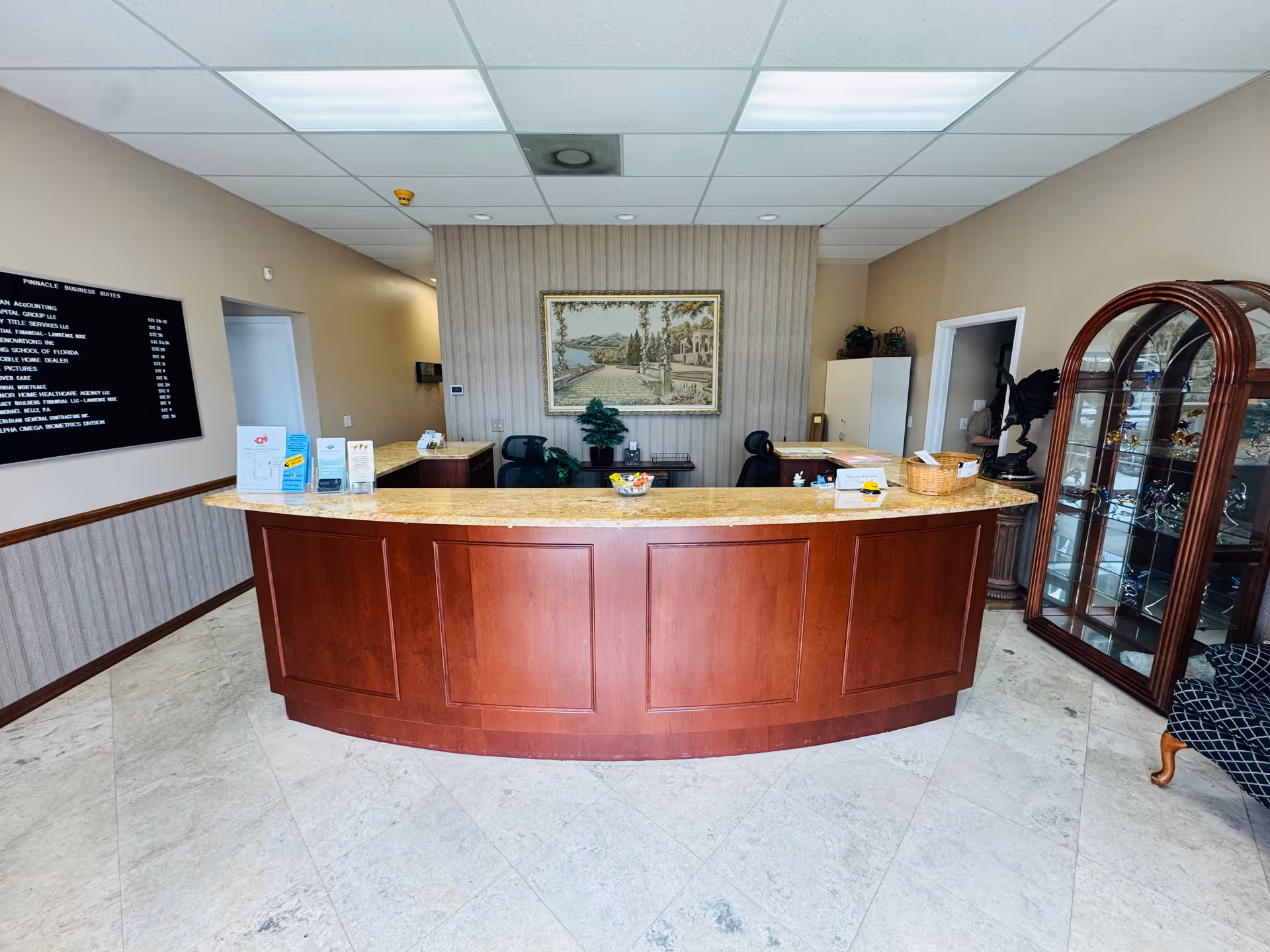 Senior living facility lobby with curved wooden reception desk and display cabinet.
