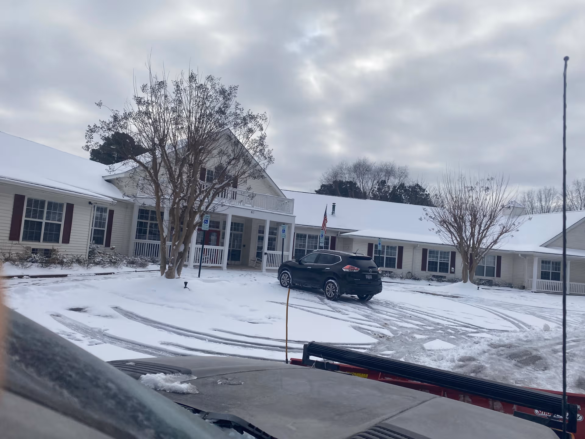 Snowy daytime view of Brookdale Wake Forest entrance with parked car in front.