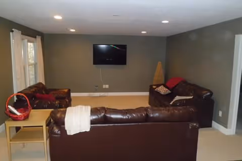 Cozy living room with brown leather sectionals, a wall-mounted TV, and a side table.