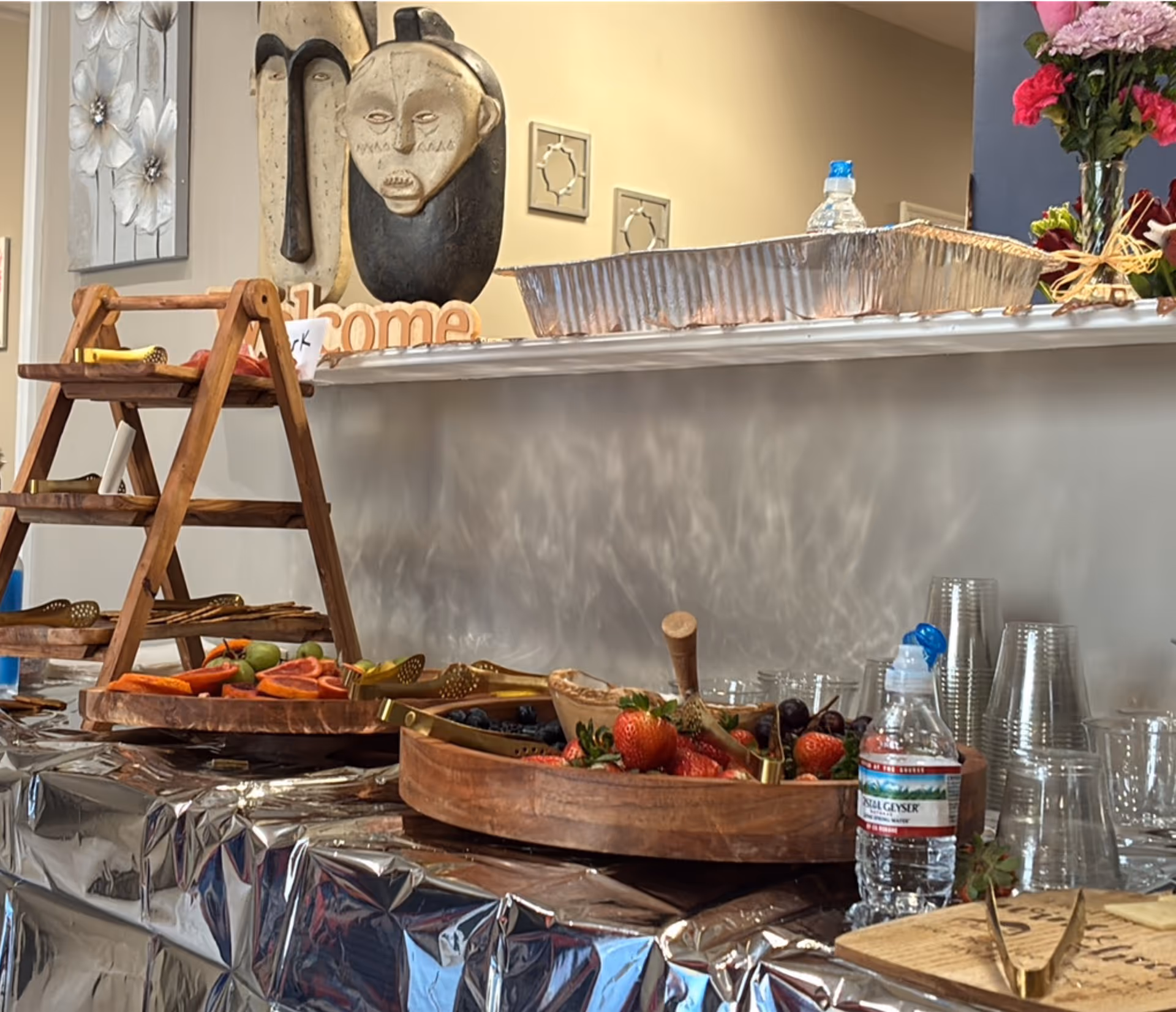 Interior dining area with foil-covered buffet, fruit trays, water bottles, and plastic cups.