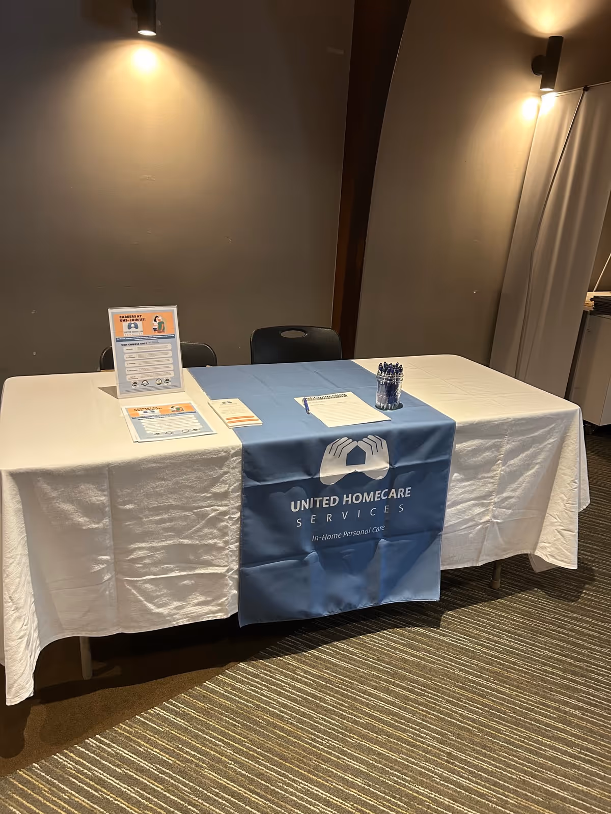 Registration table with United Homecare Services banner in an indoor setting.