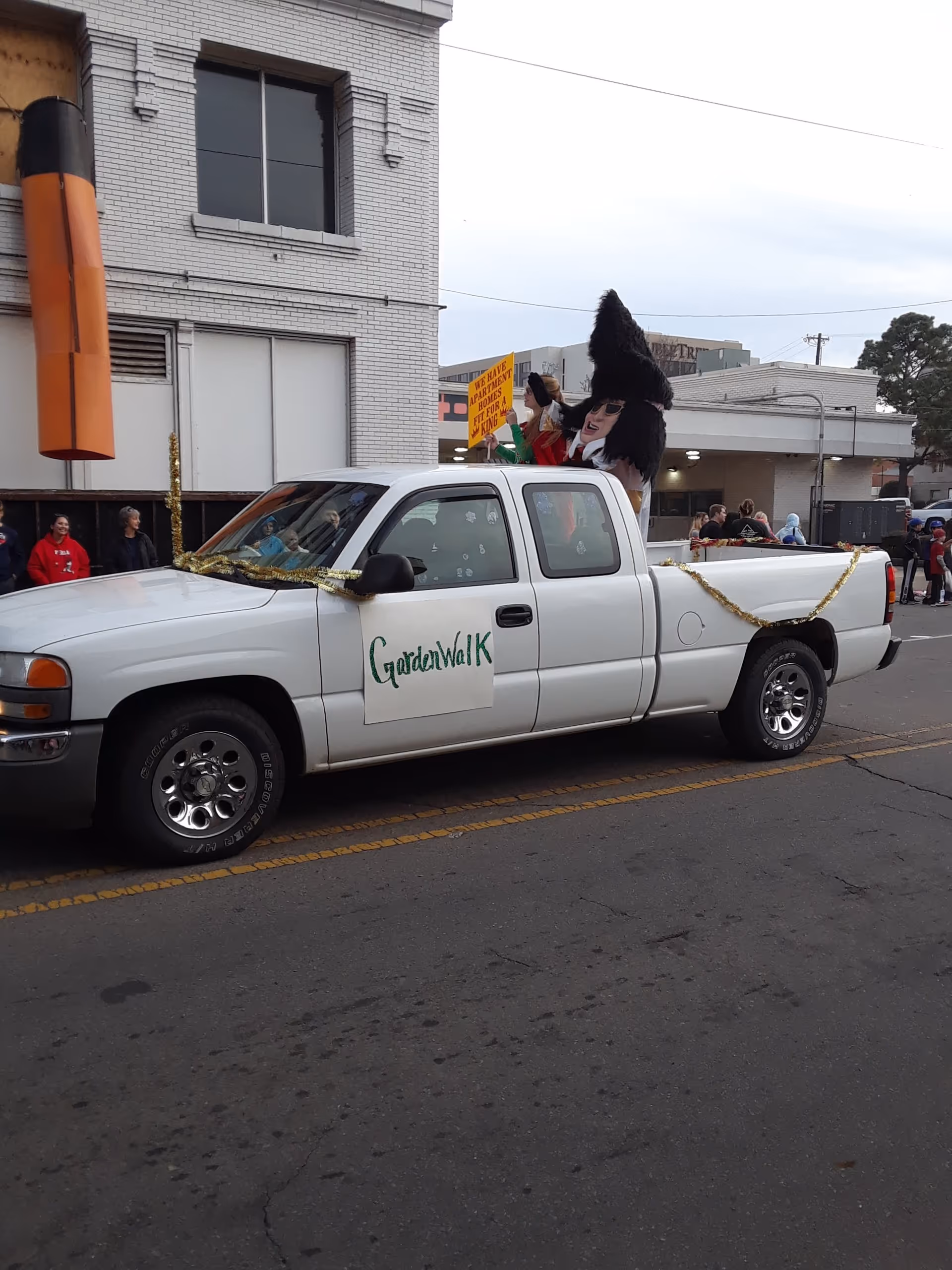 White pickup truck decorated for a parade travels down a city street.