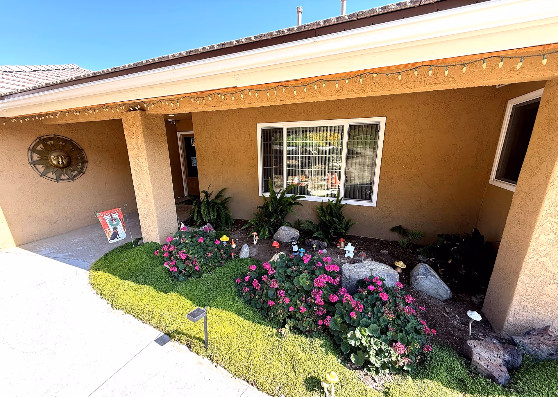 Front porch of Villa Living with a landscaped garden, flowering bushes, and decorative stones.