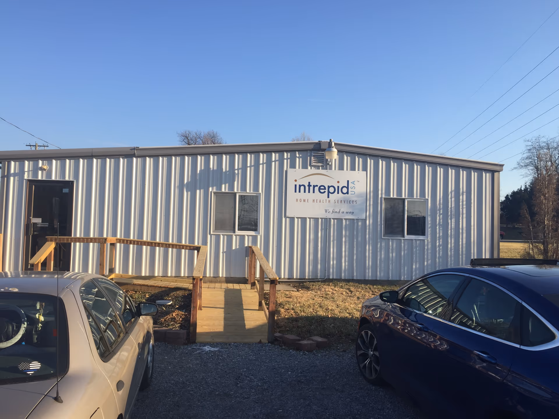 Exterior view of a metal building with Intrepid Home Health Services sign and cars.